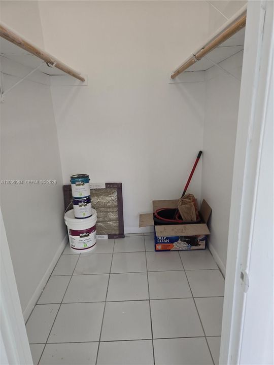 Storage closet featuring ceramic tile flooring, neutral walls, and dual built-in overhead shelves with hanging rods