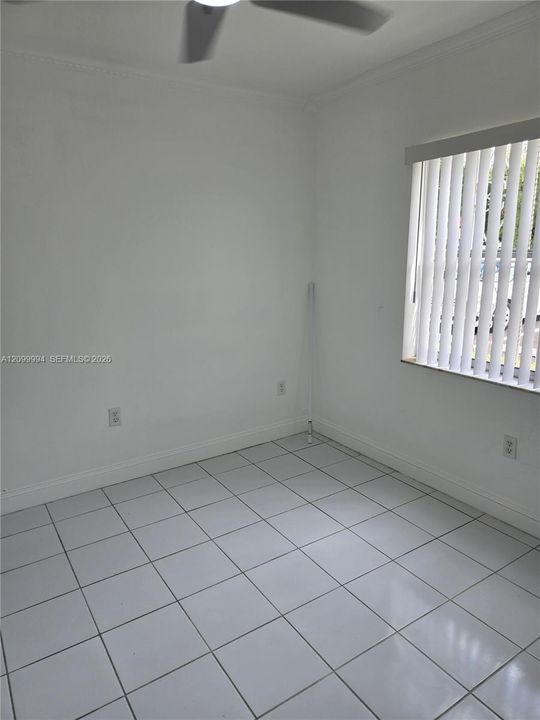Neutral-toned ceramic tile flooring, ceiling fan, and window featuring vertical blinds