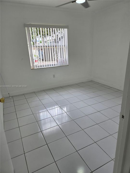 Interior space featuring white ceramic tile flooring, a window with vertical blinds, and a ceiling fan