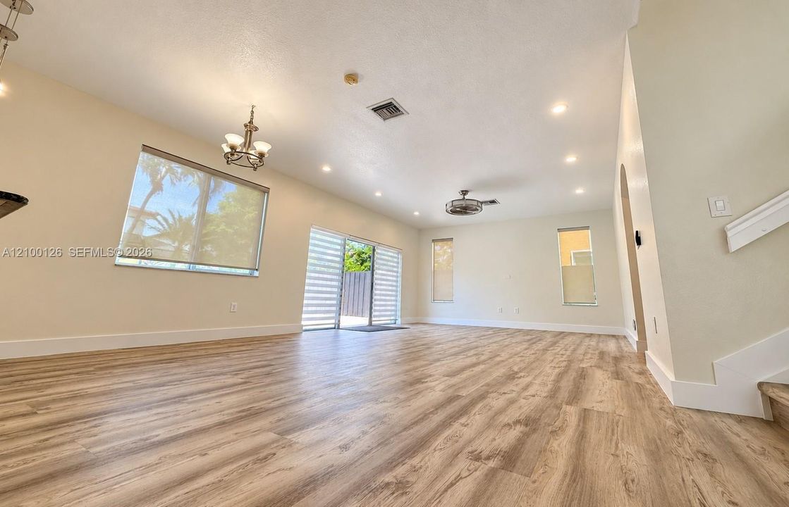 Open-concept interior featuring wood-finish flooring, recessed lighting, a ceiling fan, and sliding glass doors with roller shades