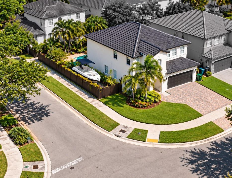 Two-story residence featuring a tile roof, paver driveway, attached two-car garage, and fenced side yard