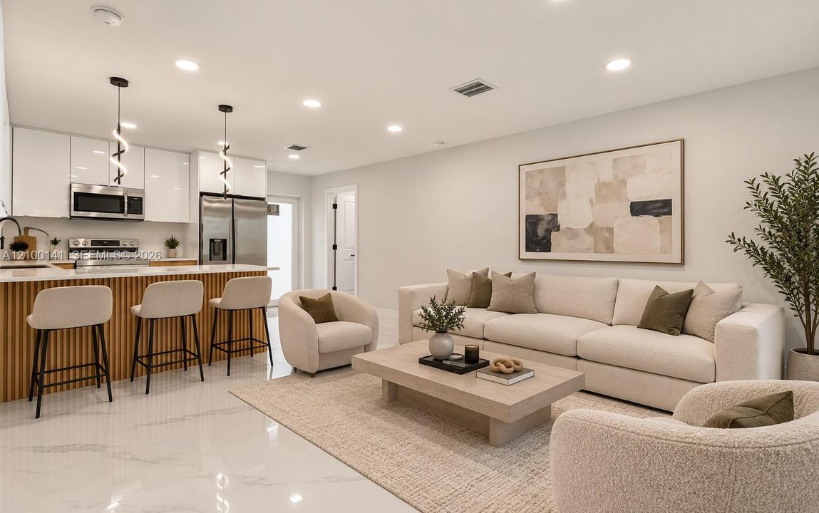 Kitchen featuring high-gloss white cabinetry, stainless steel appliances, and a fluted wood-finish kitchen island with stone-surface countertop, complemented by recessed lighting and large-format tile flooring