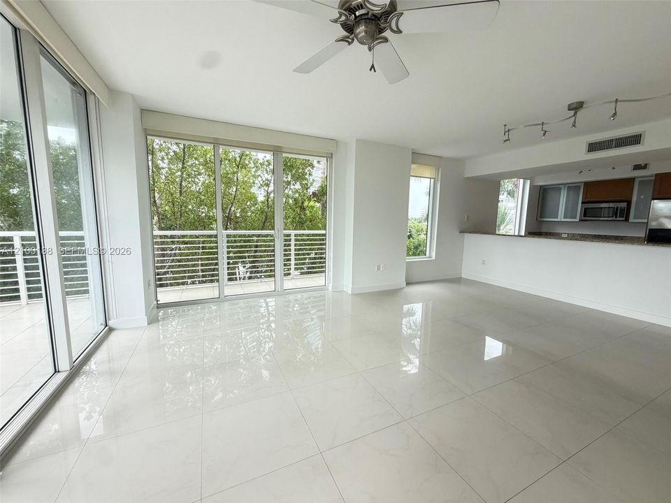 Open-concept interior featuring large-format tile flooring, floor-to-ceiling glass sliding doors, a breakfast bar with stone-finish countertops, and a track lighting system