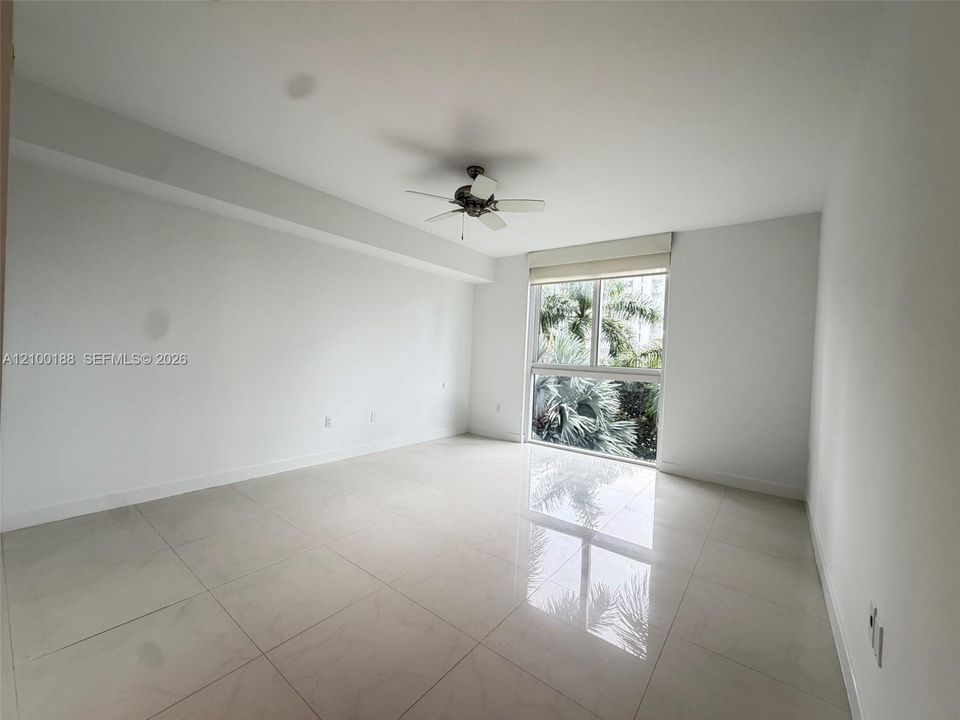 Neutral-toned interior space featuring polished tile flooring, ceiling-mounted fan, and floor-to-ceiling windows