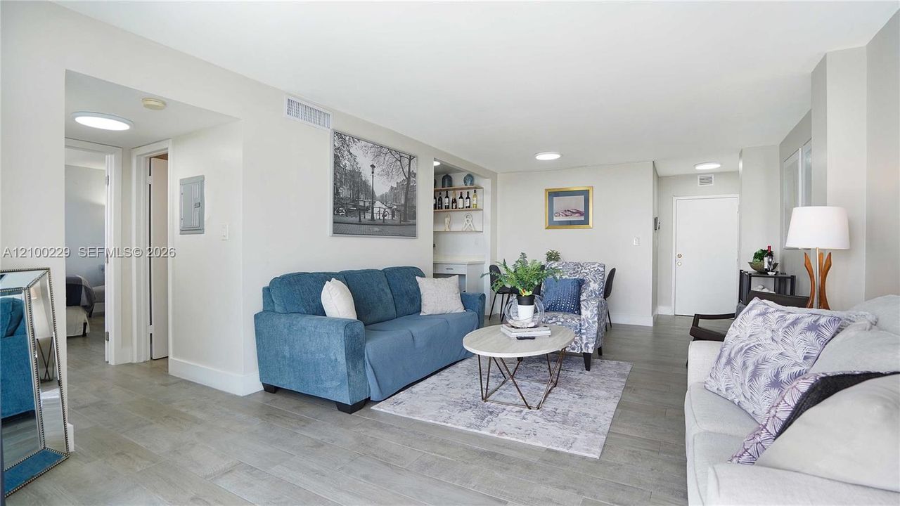 Open-concept living space featuring wood-finish flooring, neutral wall paint, recessed ceiling lighting, and a built-in recessed shelving nook
