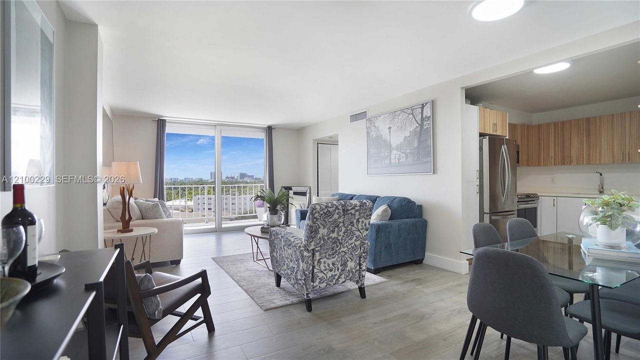 Open-concept living space featuring wood-finish flooring, floor-to-ceiling glass sliding doors, stainless steel kitchen appliances, and flat-panel cabinetry