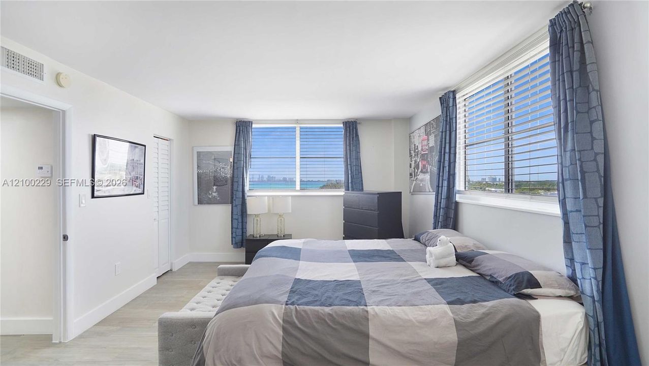 Neutral-toned interior space featuring light-toned flooring, multi-pane windows, and water-inclusive horizon scenery