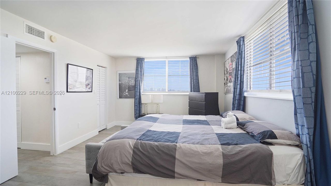 Neutral-toned interior featuring horizontal window blinds, tile flooring, and louvered closet doors