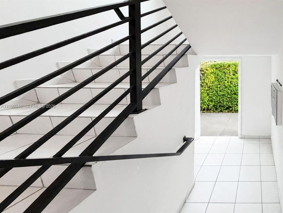 Staircase featuring matte black metal horizontal-bar railing, integrated handrail, and ceramic tile steps
