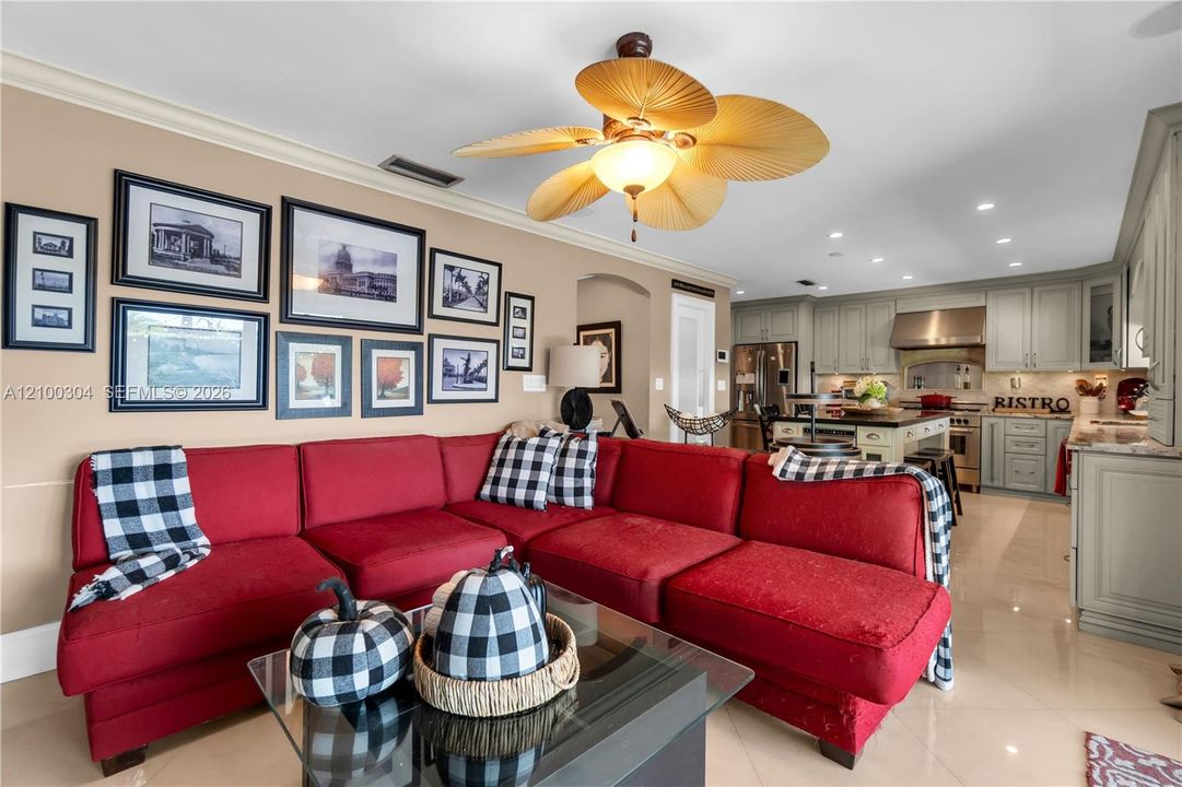 Open-concept space featuring a ceiling fan with palm-leaf style blades, recessed lighting, polished tile flooring, and custom cabinetry with stainless steel appliances