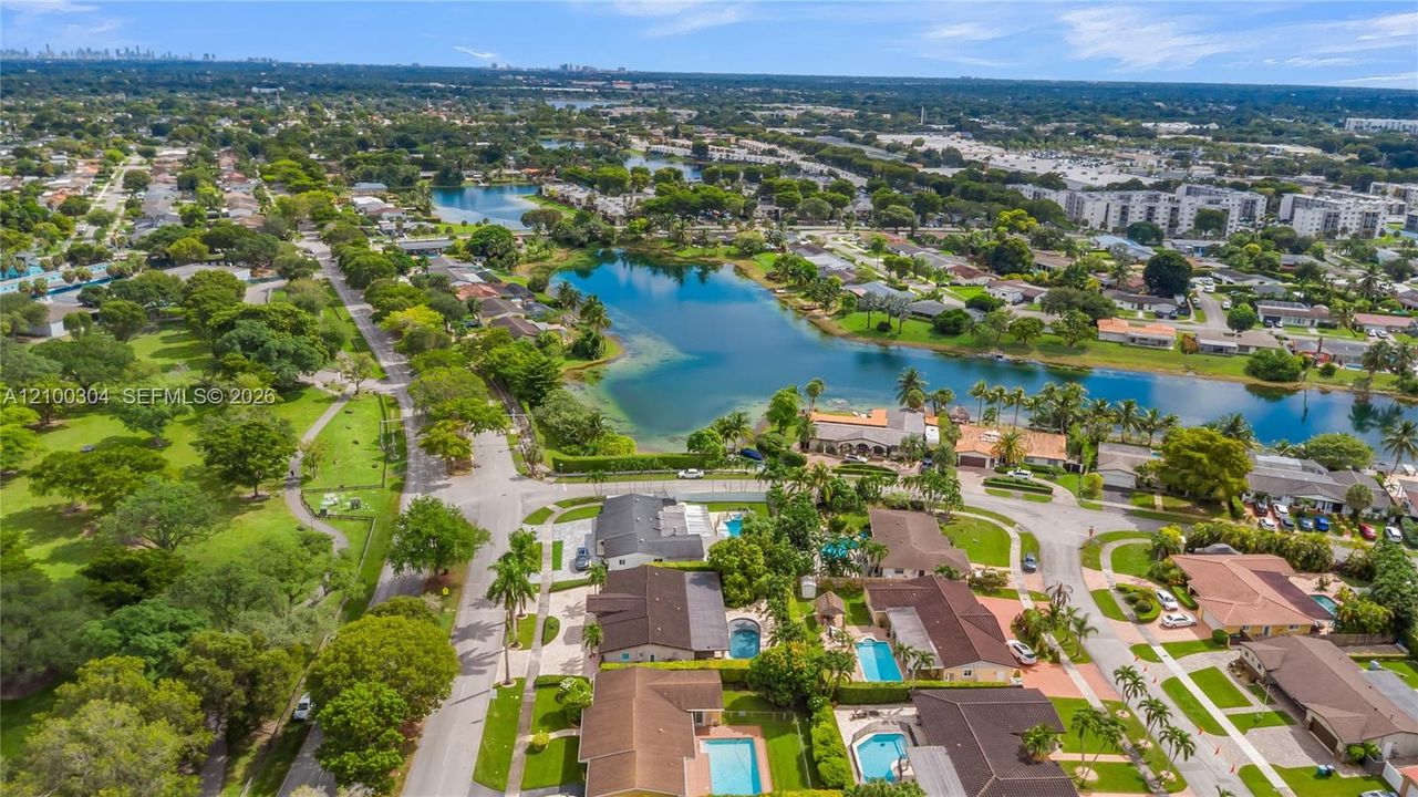 Aerial perspective featuring a waterfront setting, expansive green space, mature tree canopy, and residential streetscape
