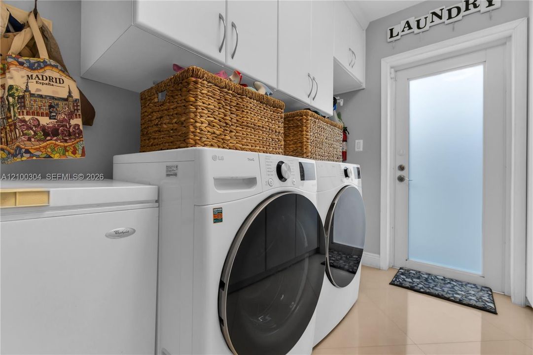 Laundry area featuring white shaker-style wall-mounted cabinetry, tile flooring, and a frosted glass-paneled exterior door