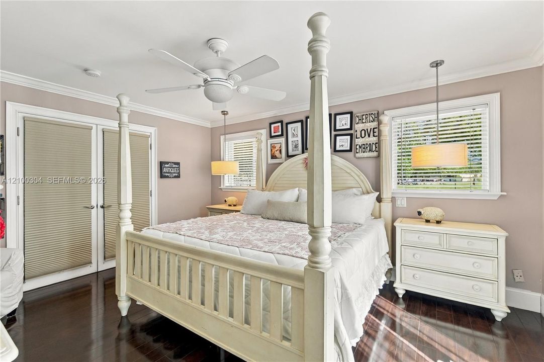 Dark-toned wood-finish flooring, white five-blade ceiling fan, dual hanging pendant lights, and double glass-paned doors