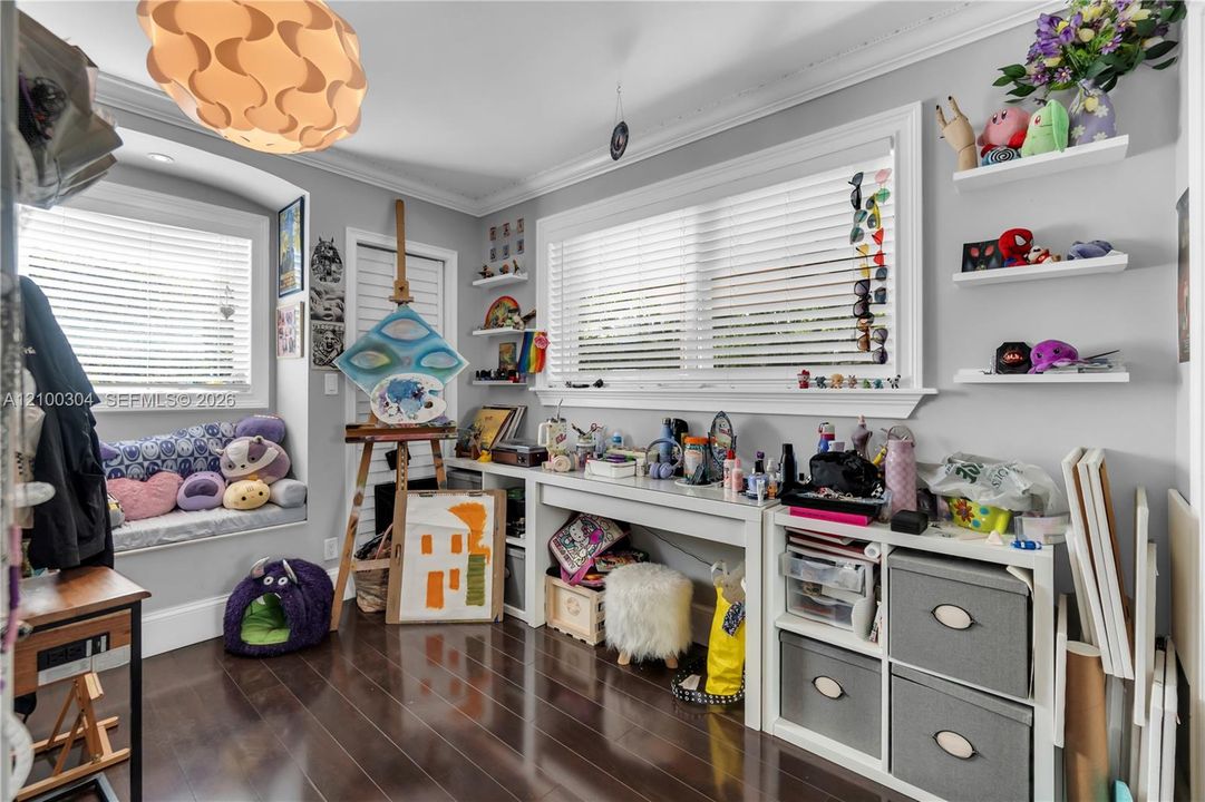 Wood-finish flooring, built-in window seat, recessed lighting, crown molding, and wall-mounted shelving