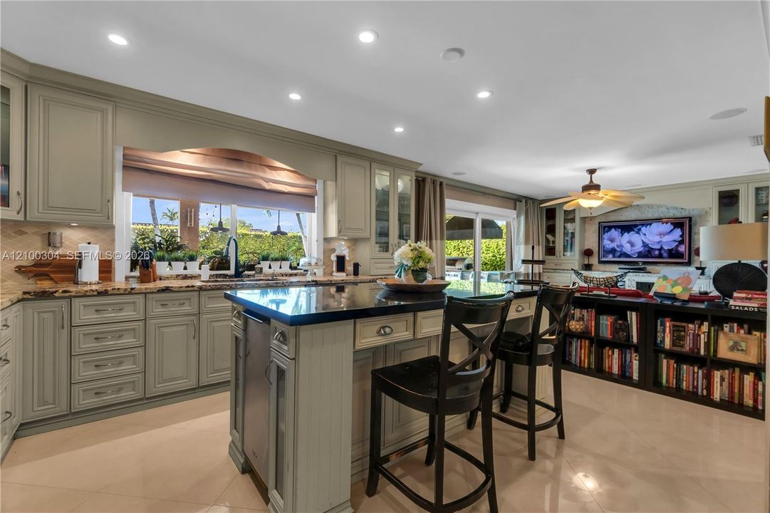 Kitchen featuring sage-toned cabinetry, stone countertops, central island, built-in shelving, and recessed lighting