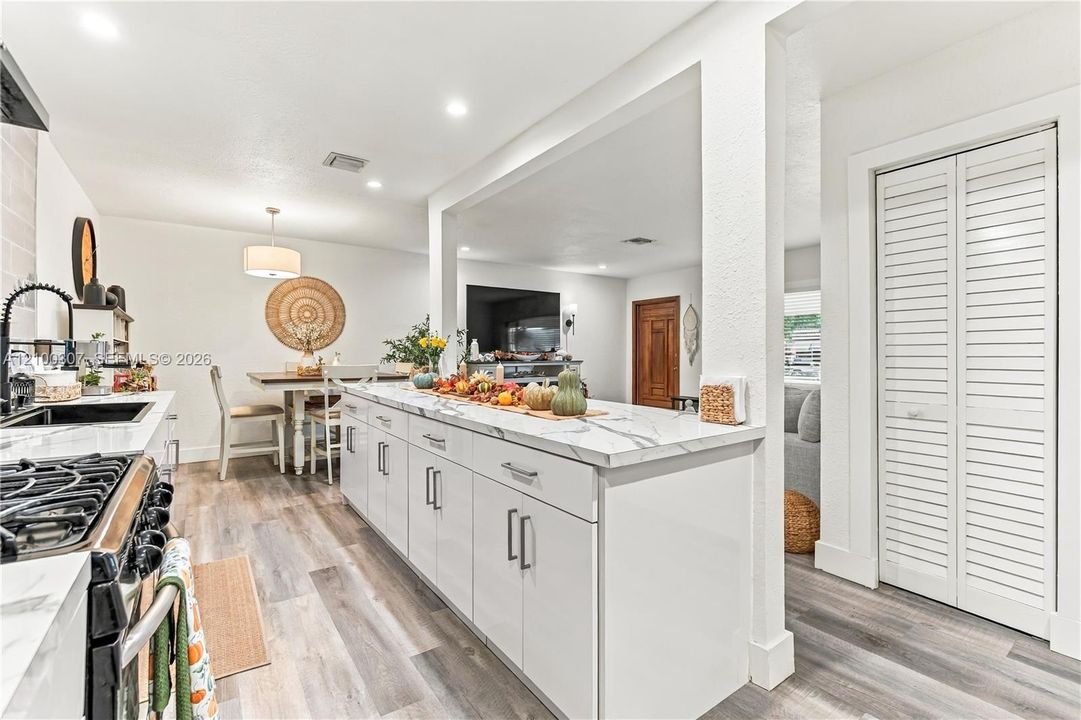 Kitchen featuring white cabinetry, stone-patterned countertops, wood-finish flooring, recessed lighting, and louvered-style bi-fold closet doors