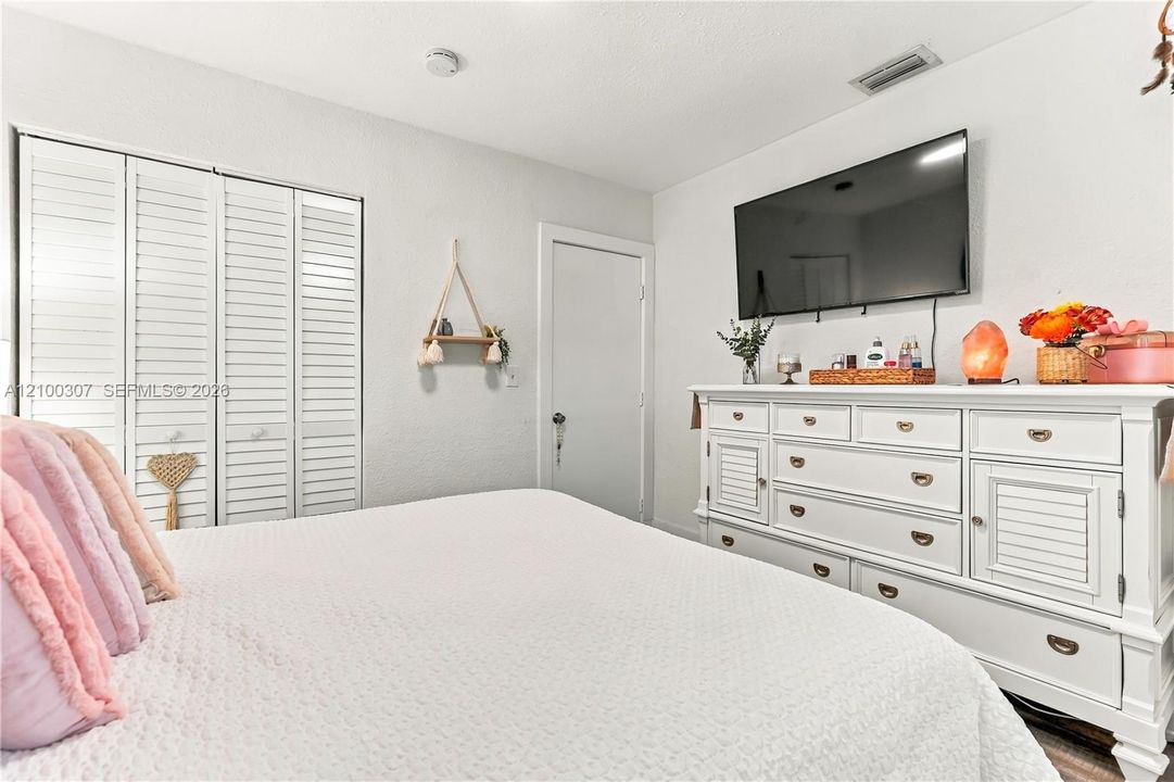 Room featuring white louvered bifold closet doors and textured walls