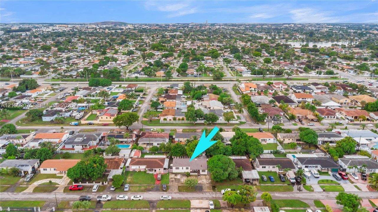 Aerial perspective featuring a single-story residence with a pitched roof, front-facing covered entry, and mature perimeter landscaping