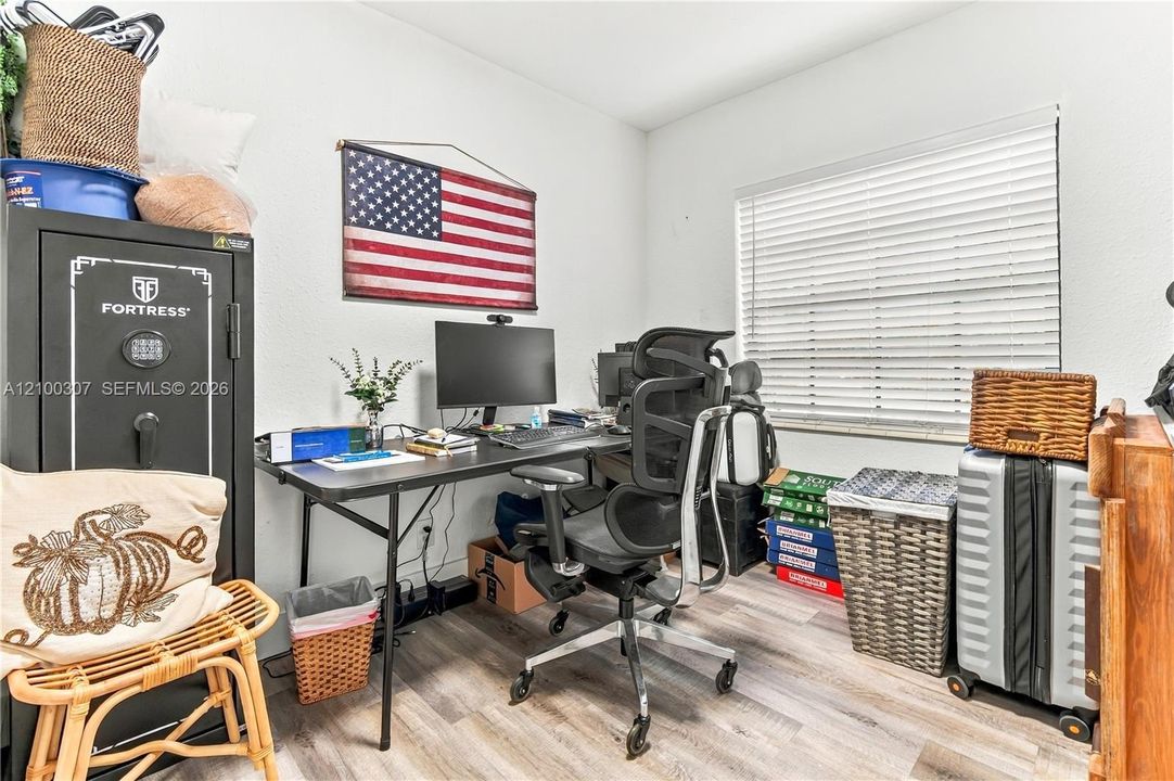Room featuring wood-finish flooring and a window with horizontal blinds