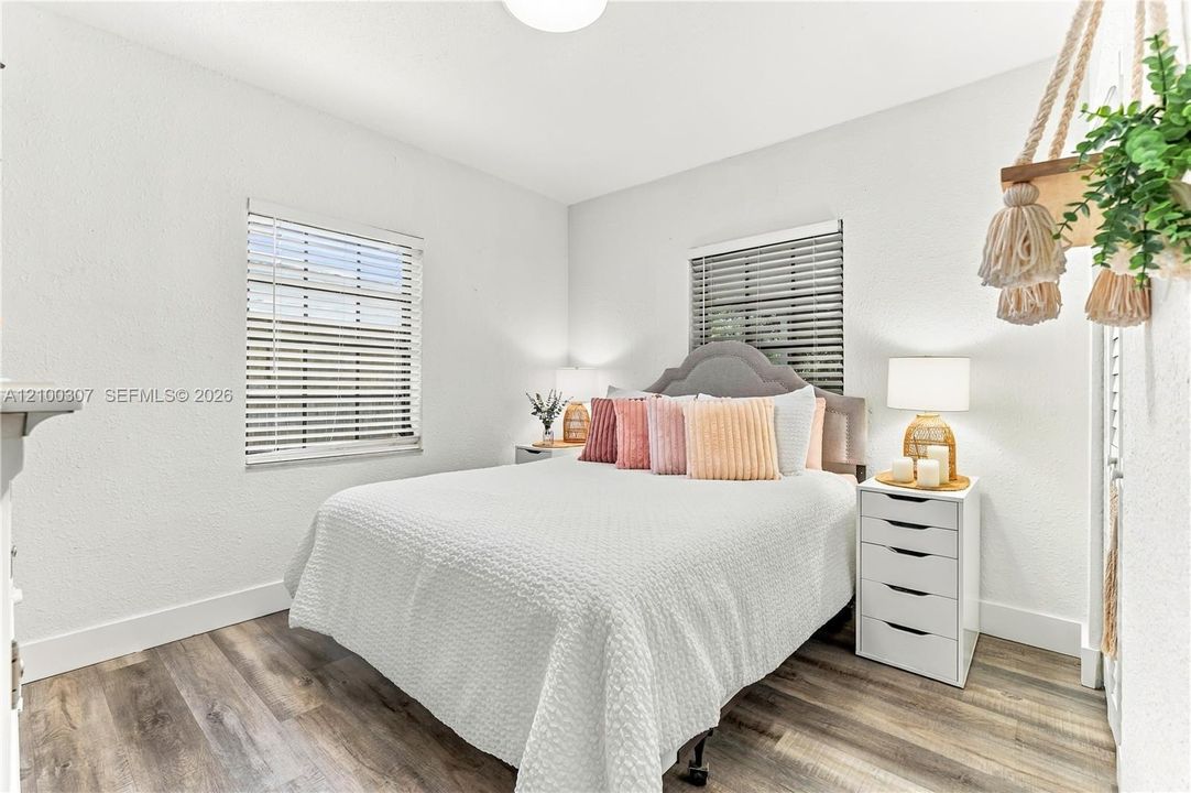 Interior room featuring wood-finish flooring, crisp white walls, and two windows with integrated horizontal blinds