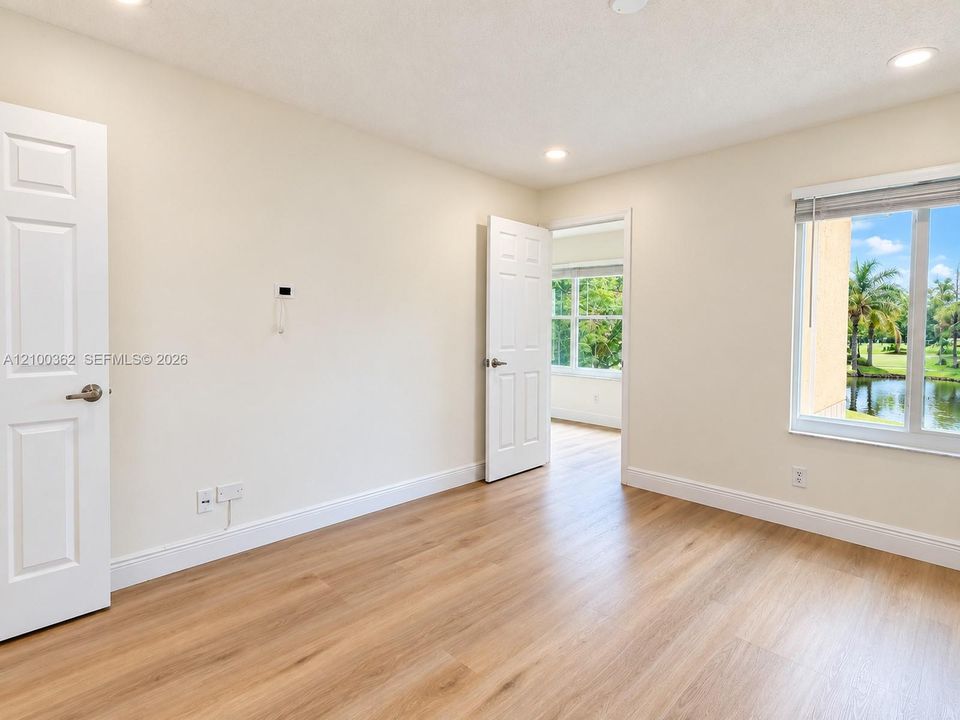 Alternate view of the primary bedroom featuring large windows with peaceful lake views and modern finishes.