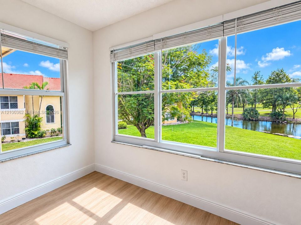 Stunning lake view from bright living space with natural light, impact windows, and wood-look floors.