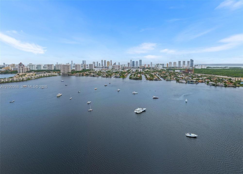 Aerial perspective featuring an expansive coastal waterway with moored watercraft and a distant city skyline