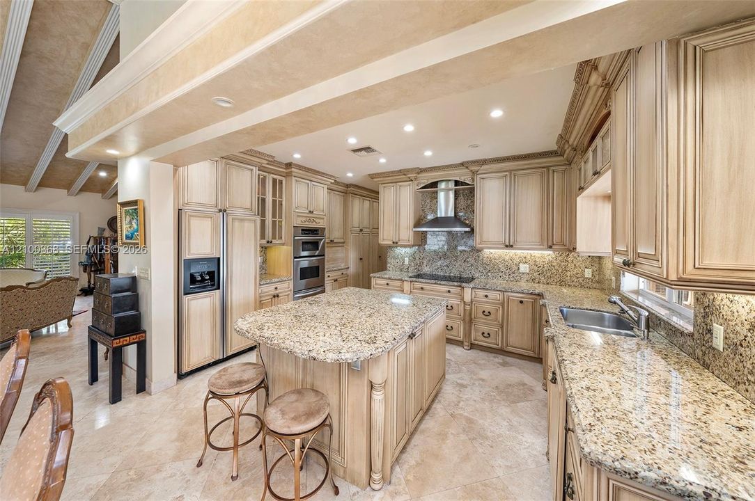 Kitchen featuring custom cabinetry with detailed millwork, stone countertops, a central island, recessed lighting, and stainless steel appliances