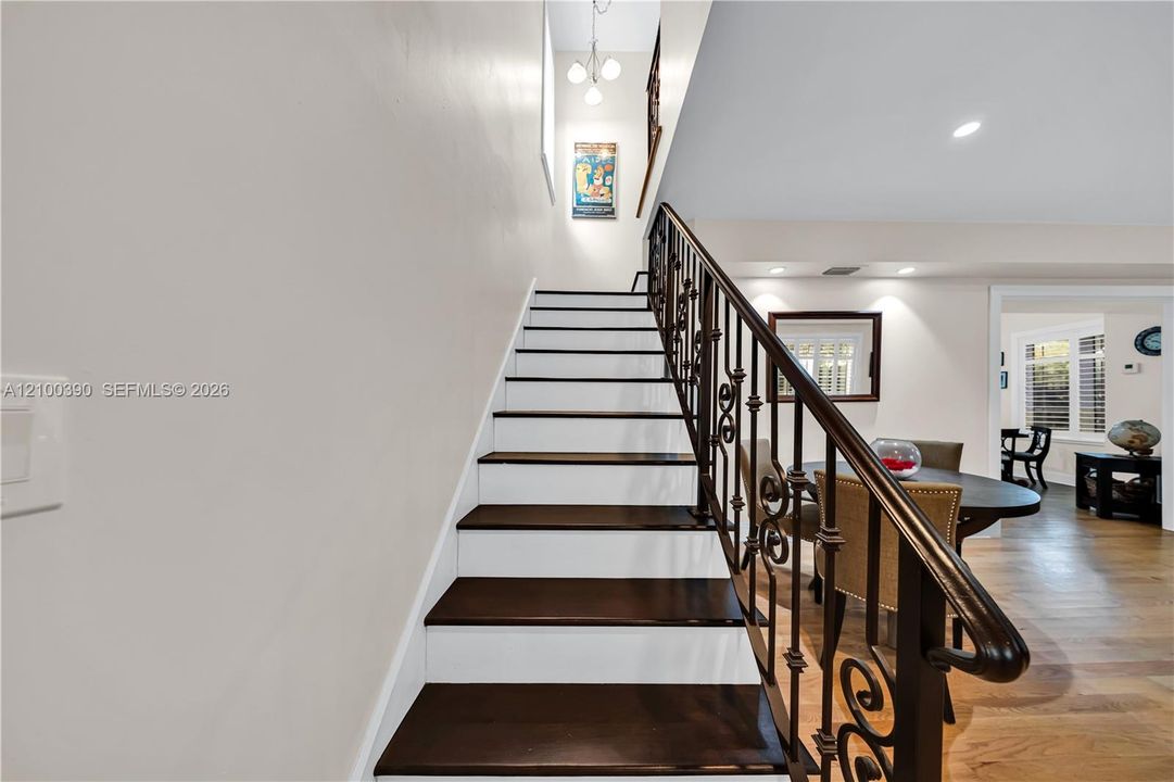 Staircase featuring dark wood-finish treads, white risers, and decorative wrought-iron balusters with a dark wood handrail