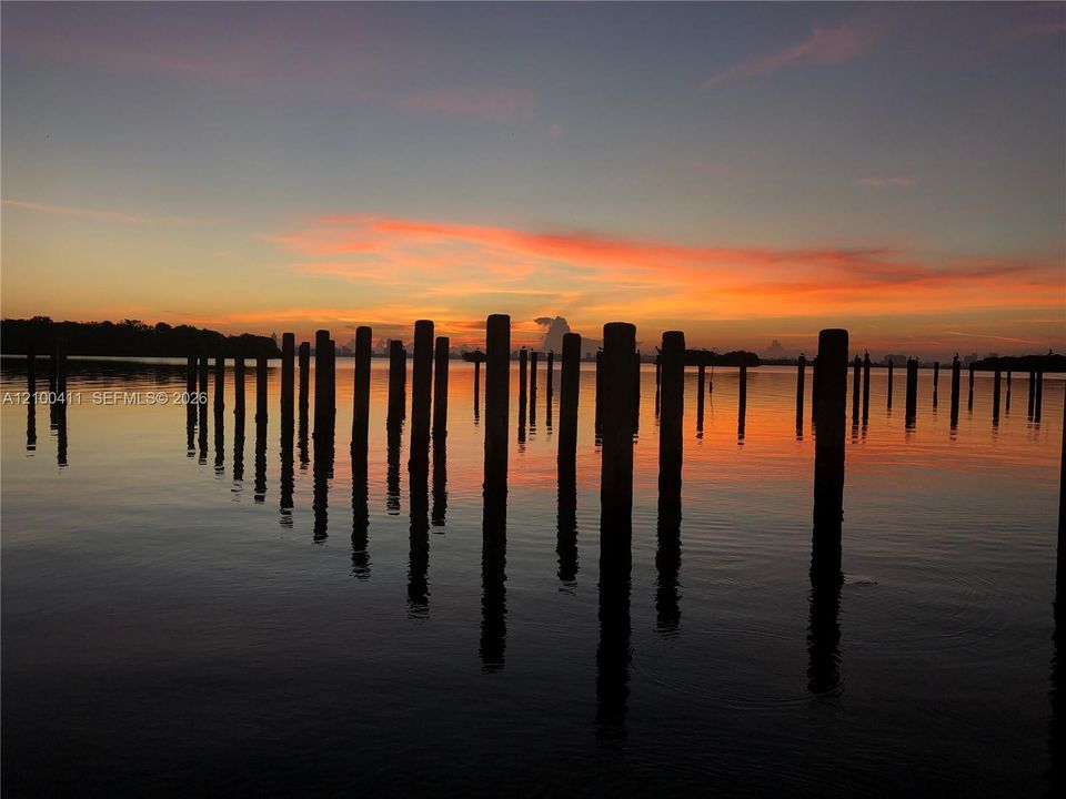 Waterfront bulkhead pilings set against a colorful sunset backdrop