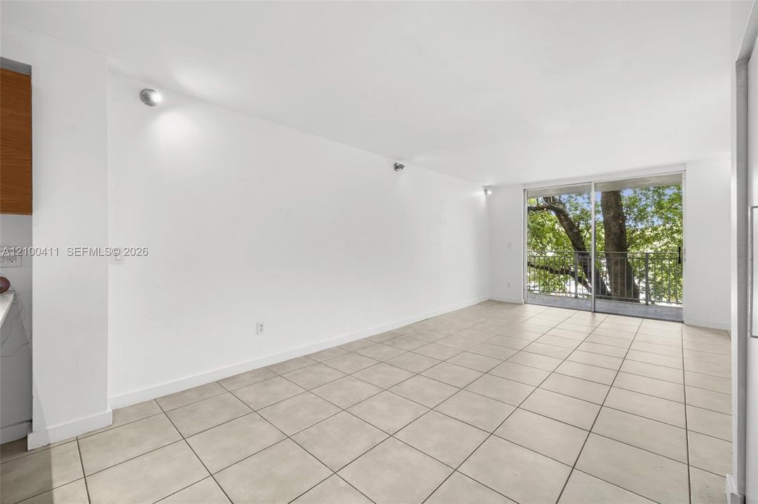 Open floor plan featuring ceramic tile flooring, recessed lighting, and a floor-to-ceiling glass sliding door leading to a balcony with metal railing