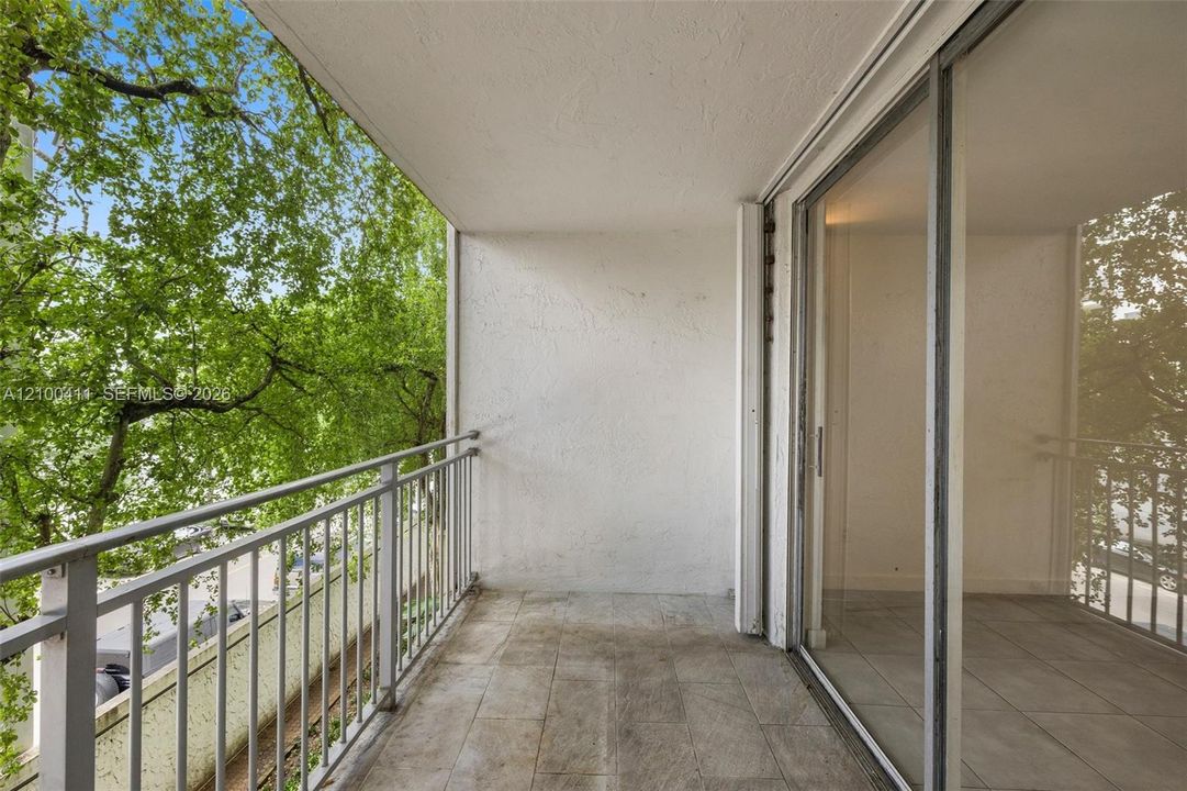 Covered balcony featuring concrete flooring, a metal railing, and sliding glass doors