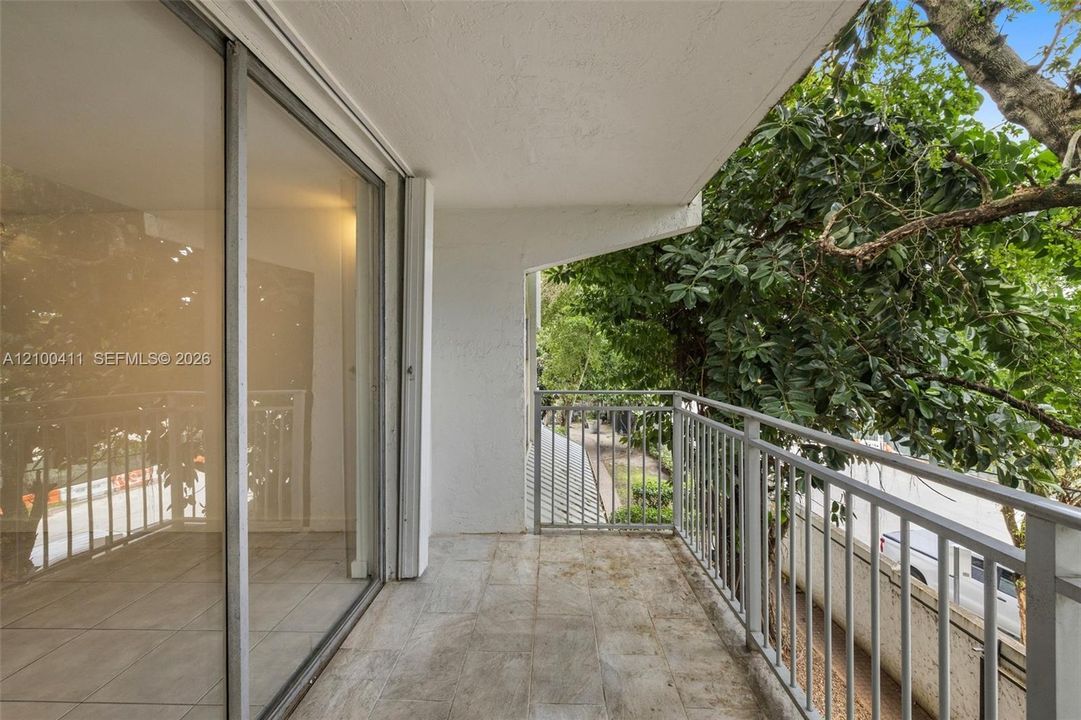 Covered balcony featuring tile flooring, metal railings, and floor-to-ceiling sliding glass doors