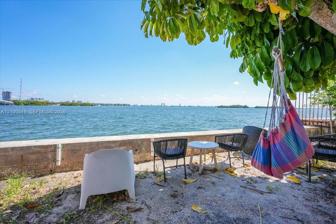 Waterfront outdoor space featuring a concrete bulkhead and mature trees