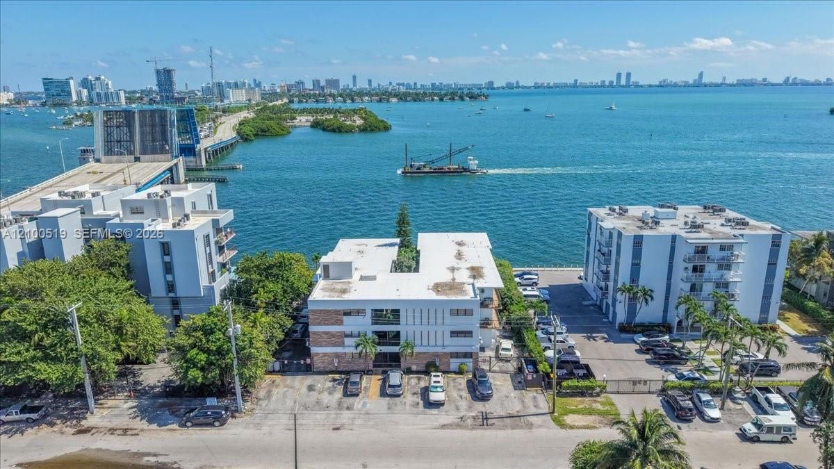 Aerial perspective of a multi-story residential complex featuring paved surface parking and waterfront proximity
