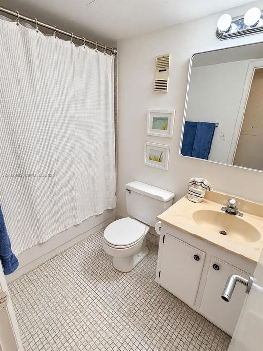 Bathroom featuring a vanity with integrated sink, rectangular wall-mounted mirror, two-light fixture, and tiled flooring