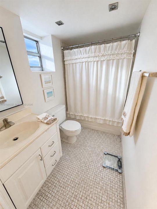 Bathroom featuring a white vanity cabinet, integrated sink with a metal faucet, mosaic tile flooring, and a tub-shower combination with recessed ceiling lighting