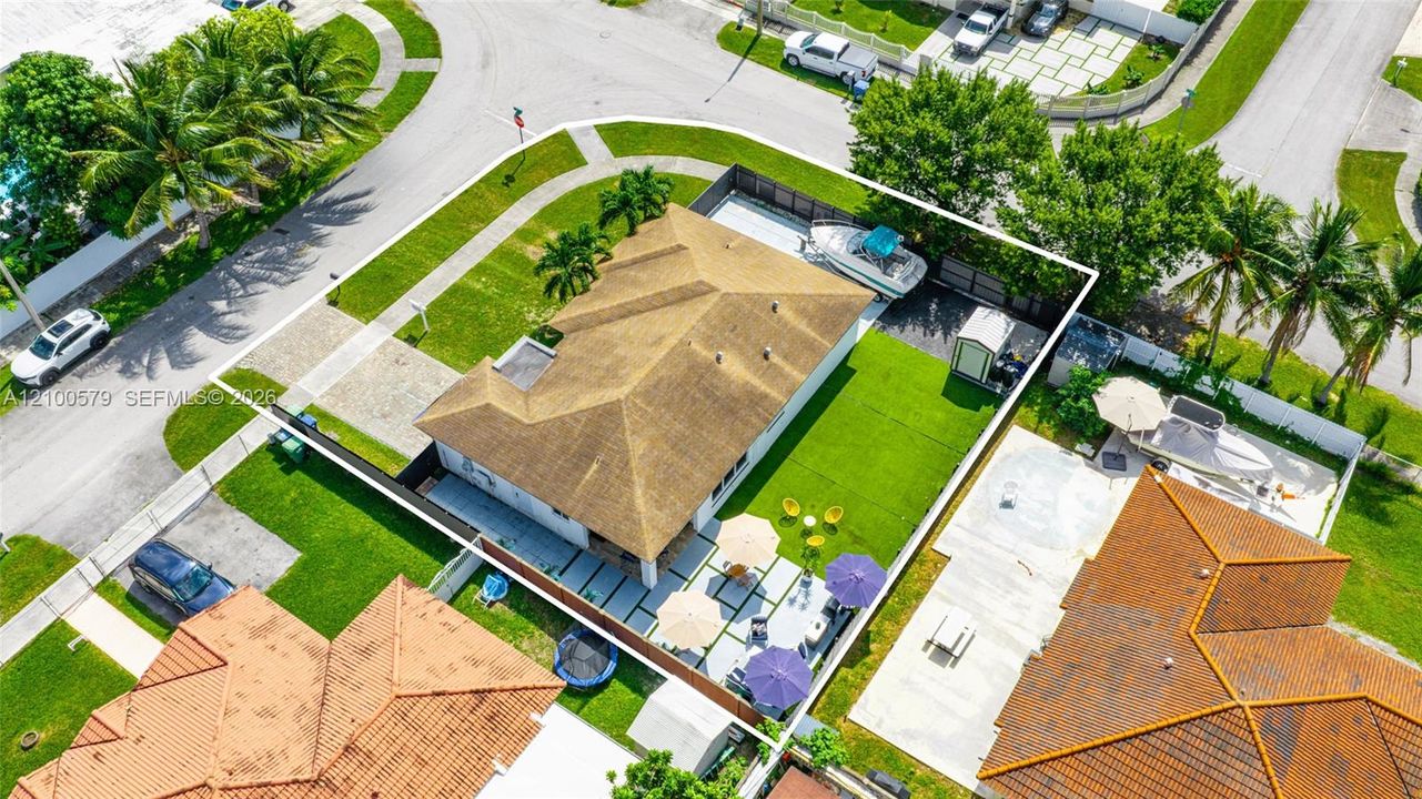 Corner lot featuring a fenced backyard, concrete paver patio, lush lawn, and side-yard boat storage area