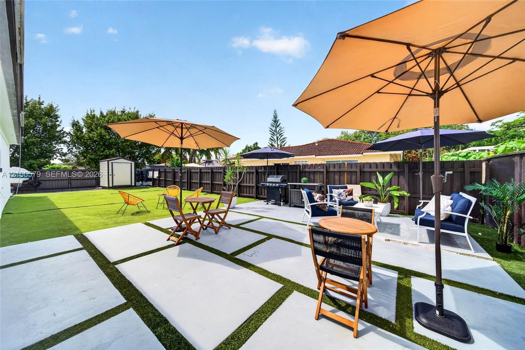 Rear exterior area featuring a concrete paver patio with turf inlays and a full-perimeter privacy fence