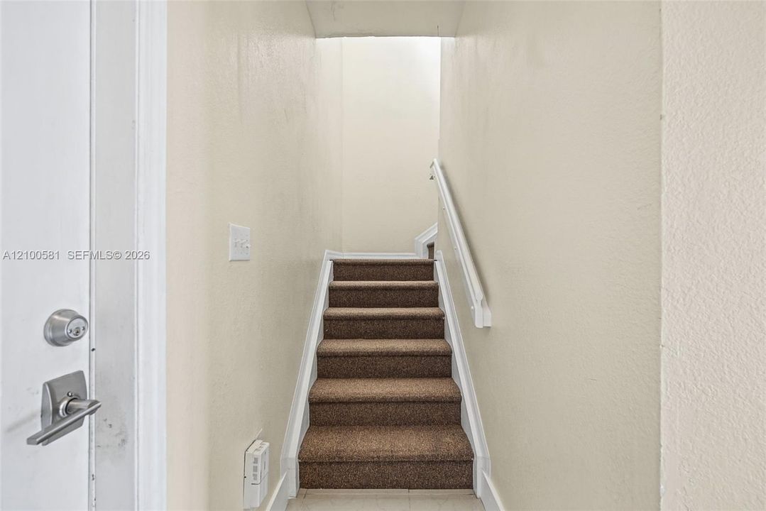 Staircase featuring wall-to-wall carpeting and a white handrail