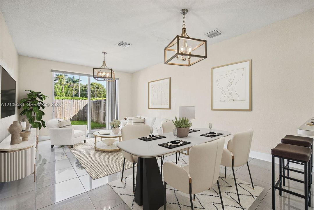 Open-concept living space featuring large-format tile flooring, dual geometric metal-frame pendant lighting, and sliding glass doors with access to an exterior fenced yard