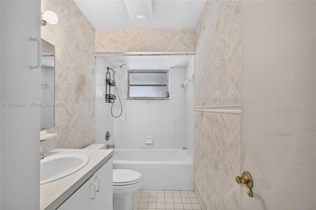 Hall bathroom featuring a vanity with a white countertop and oval sink, a combined tub and shower enclosure *