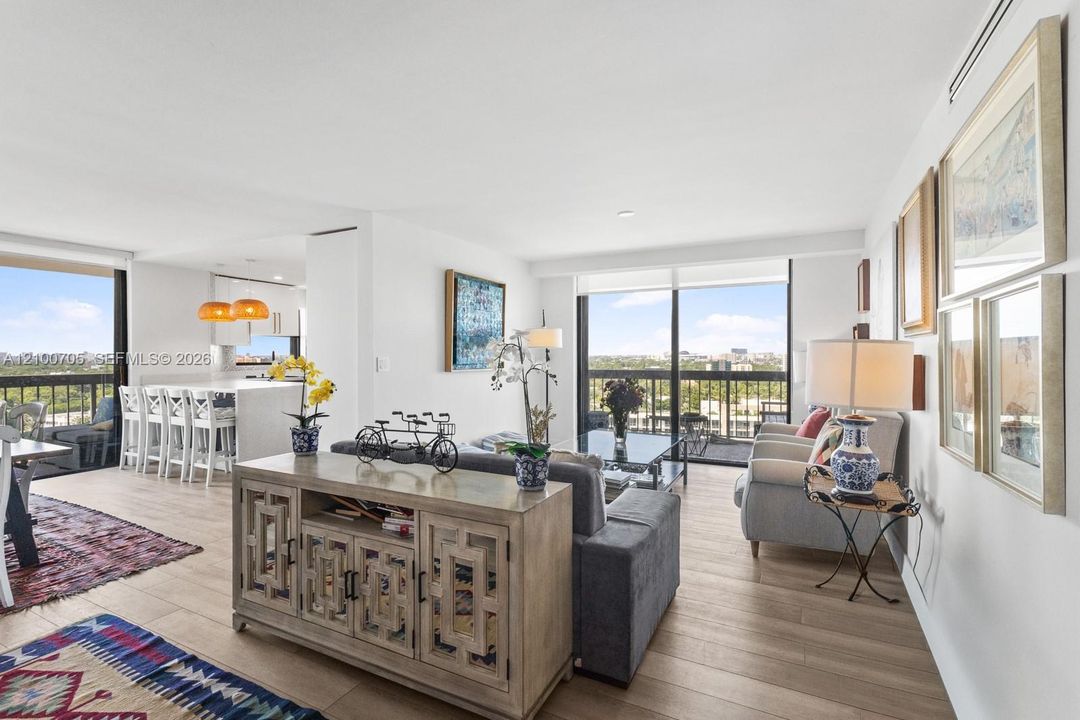 Open-concept living space featuring wood-finish flooring, floor-to-ceiling windows, recessed lighting, and a kitchen island with stone countertops