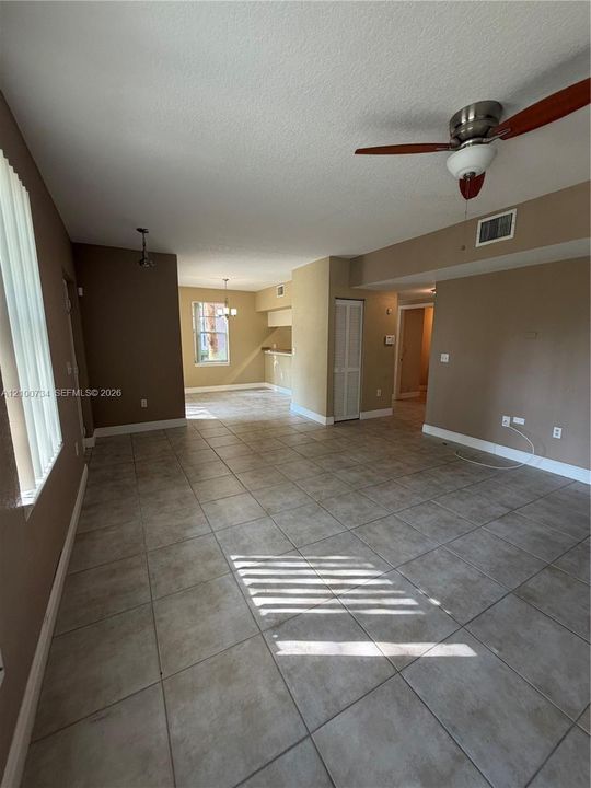 Neutral tile flooring, ceiling fan with light fixture, vertical blinds, and built-in closet with bifold doors
