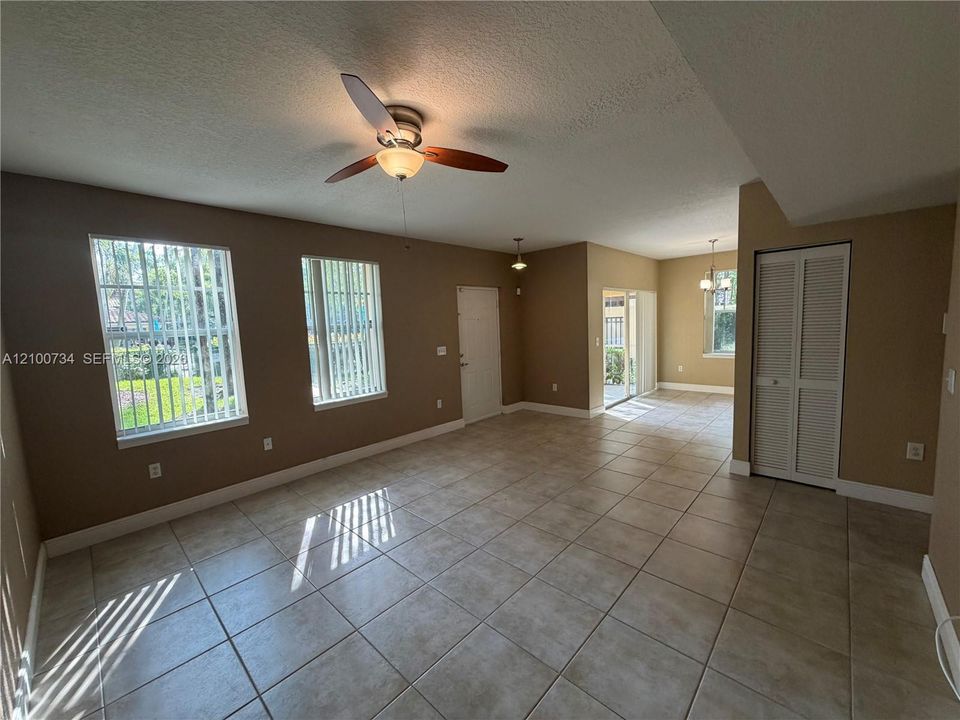 Interior space featuring neutral-toned walls, tile flooring, a ceiling fan with integrated lighting, and vertical window blinds