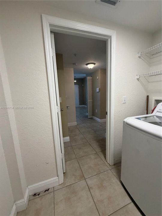 Utility space featuring large-format ceramic tile flooring, neutral wall finishes, and overhead wire shelving