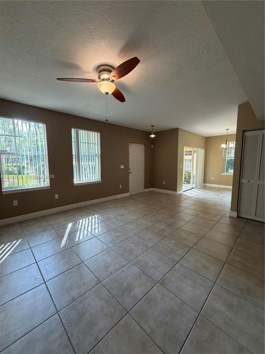 Large-format tile flooring, ceiling fan with integrated lighting, dual windows with vertical blinds, and a closet with bifold doors
