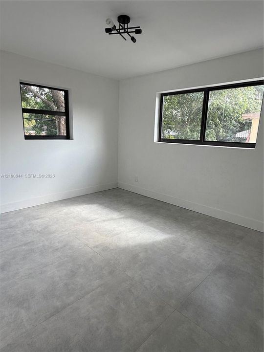 Neutral-toned large-format tile flooring, matte black window frames, and contemporary geometric ceiling lighting