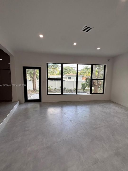 Large format tile flooring, recessed lighting, and expansive black-framed windows featuring integrated door access