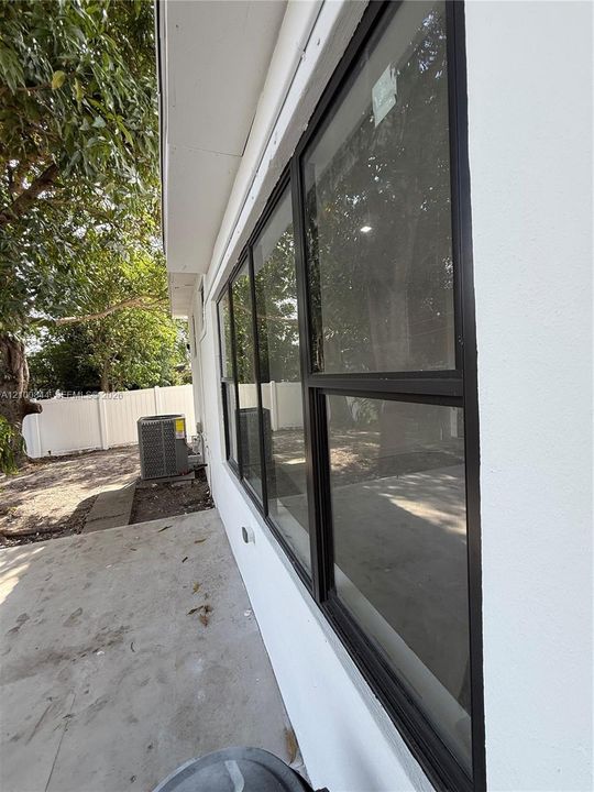 Exterior profile featuring a white stucco facade, black-trimmed windows, a concrete patio, and a white privacy fence